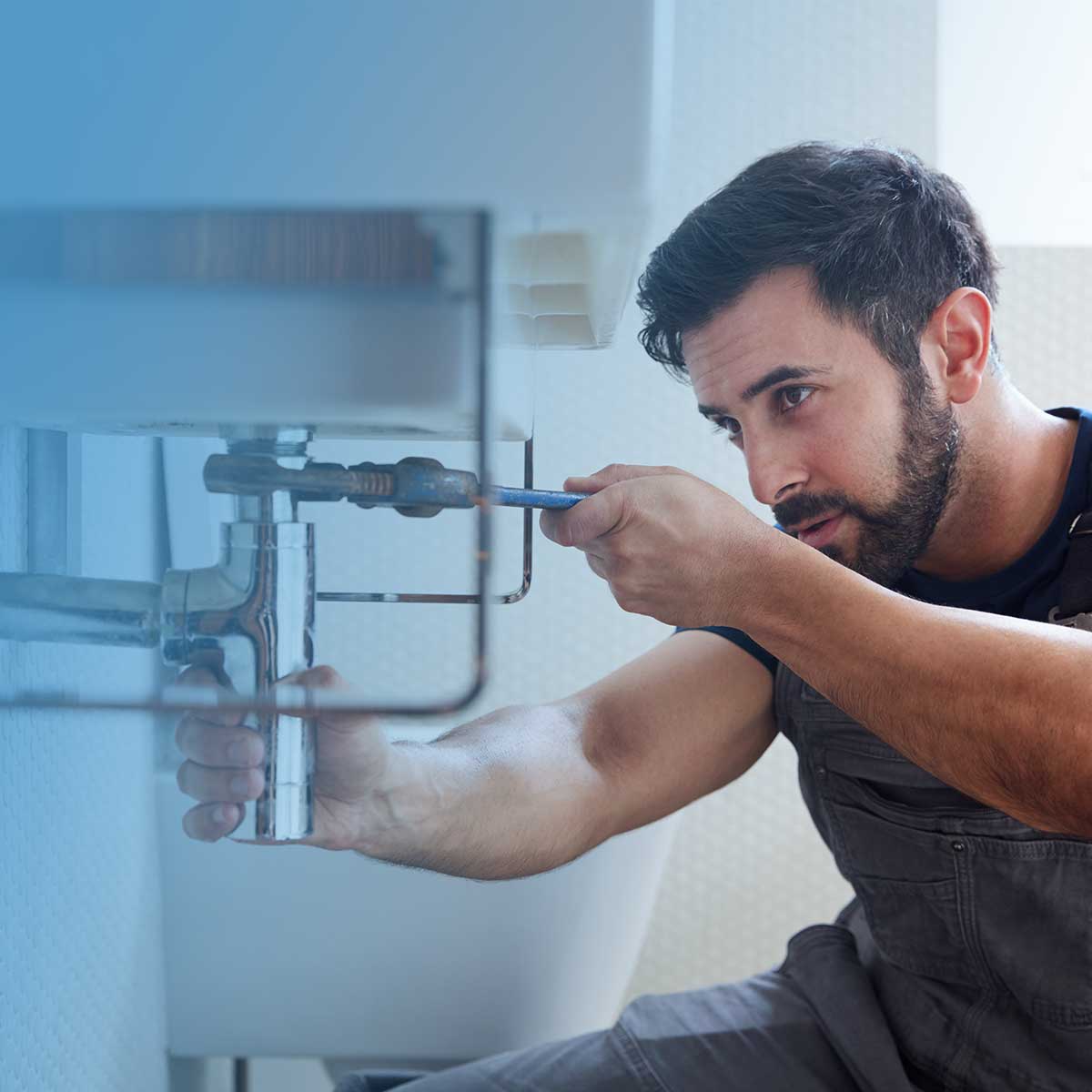 Plumber repairing pipework under a sink